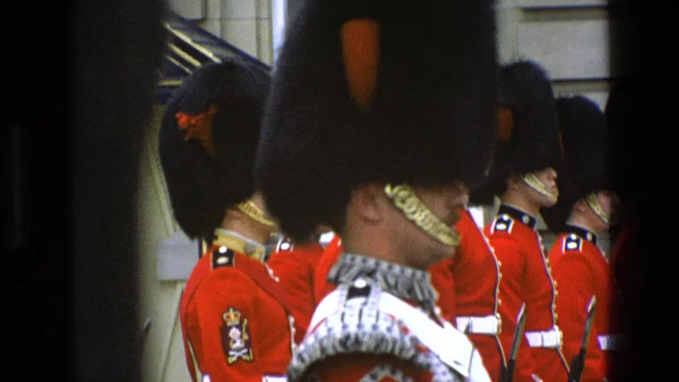 1969 Buckingham Palace guard scene filmed close to the formation, with bearskin hats, red tunics, and foreground obstruction visible.