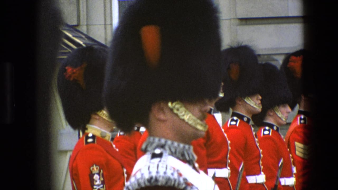 1969 England 8mm frame showing ceremonial guards in red tunics and tall black hats, partly obscured by a foreground guard and dark framing.