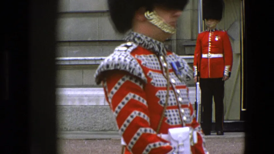 Close 1969 Buckingham Palace view of a Grenadier Guard uniform, with red tunic details and another sentry near the entrance.