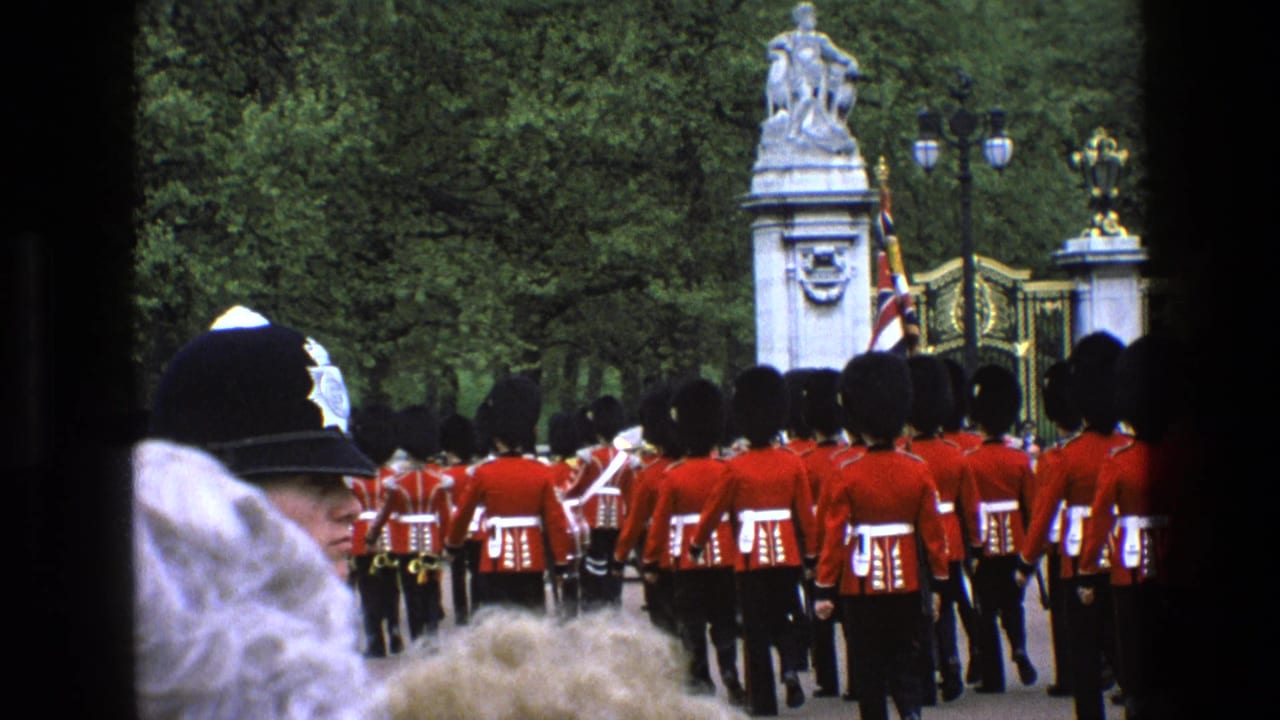 Royal guards in red tunics march toward ornate gates as spectators watch from behind.