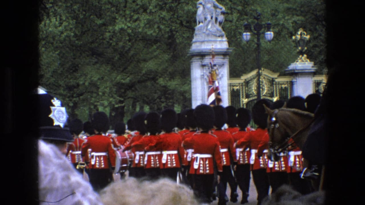 1969 England footage frame with guards in formation near ornate gates, a partial horse, and spectators visible at the edge.