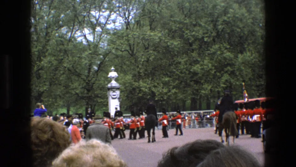 Visitor-shot 1969 England frame with spectators in front and guards, mounted riders, and a ceremonial route beyond.