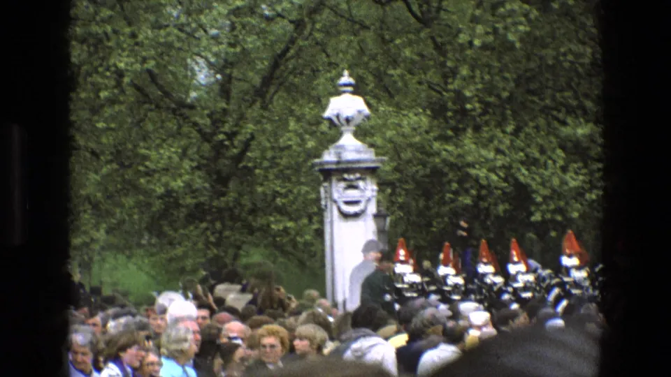 1969 England spectator view of ceremonial guards on horseback, with the crowd and stone pillar partly obscured by dark framing.
