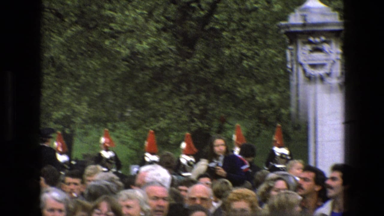 Dense crowd with ceremonial guards visible between stone pillars and trees.