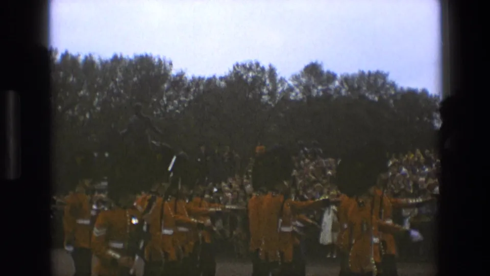 1969 England home-movie frame showing guards, horses, and spectators during a public ceremonial moment.
