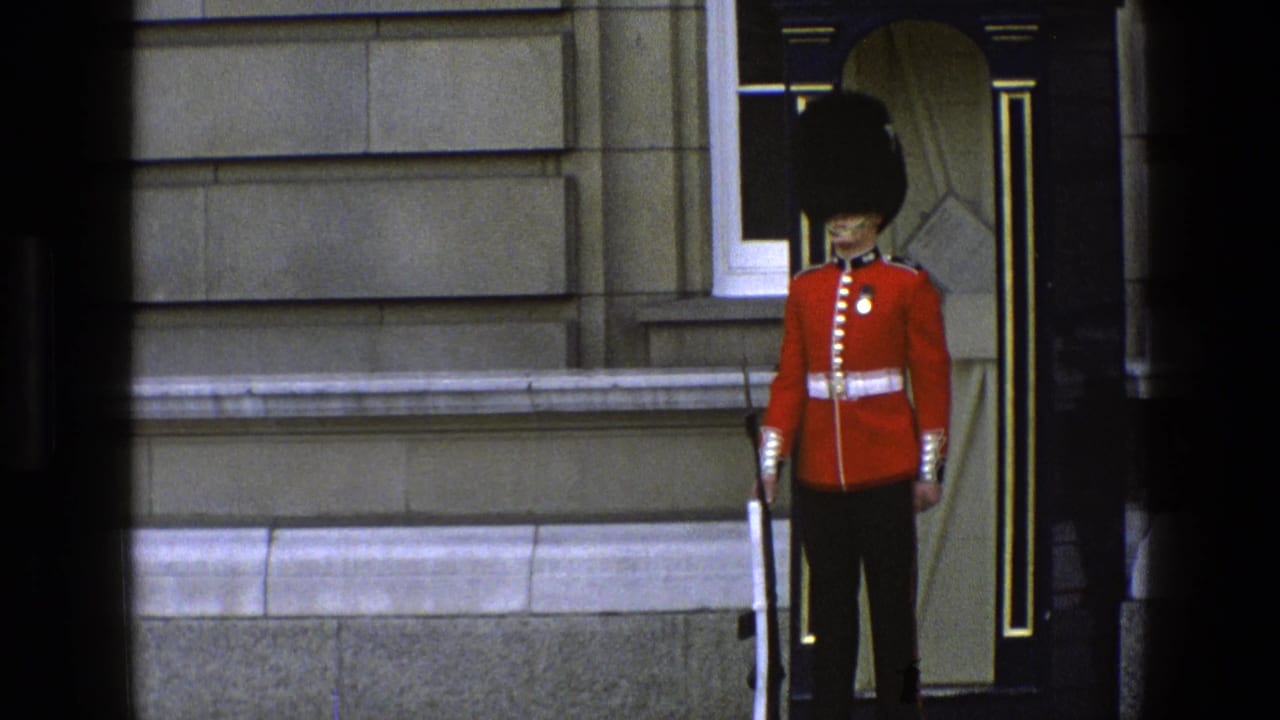 Queen's Guard in red tunic standing beside a dark doorway with a rifle.
