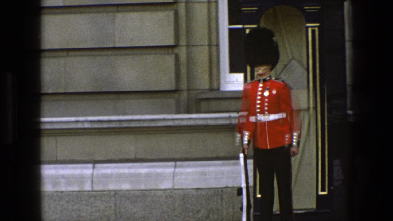 1969 England 8mm frame showing a Royal Guard in red tunic and tall black hat standing at attention by a sentry box.
