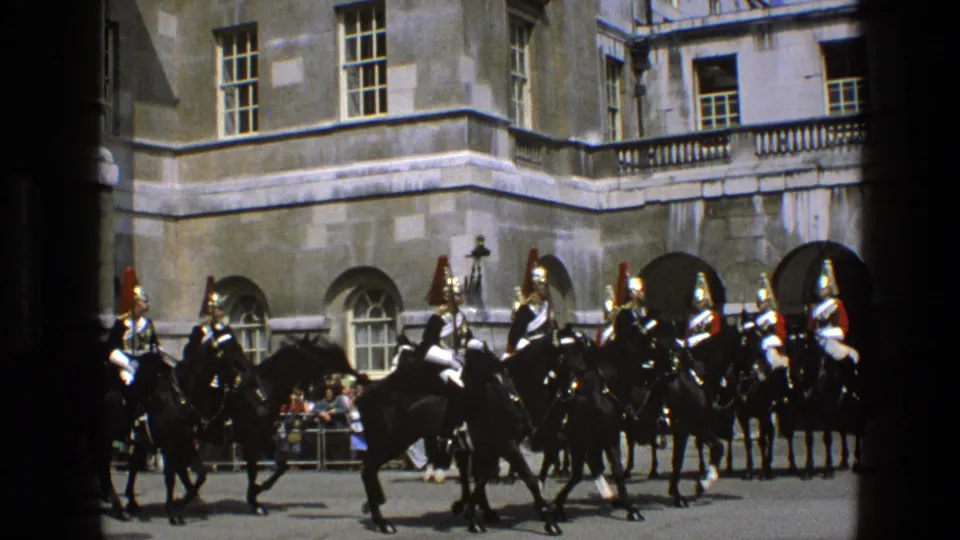 1969 England frame showing mounted ceremonial guards clustered in formation outside a grand stone building with spectators nearby.