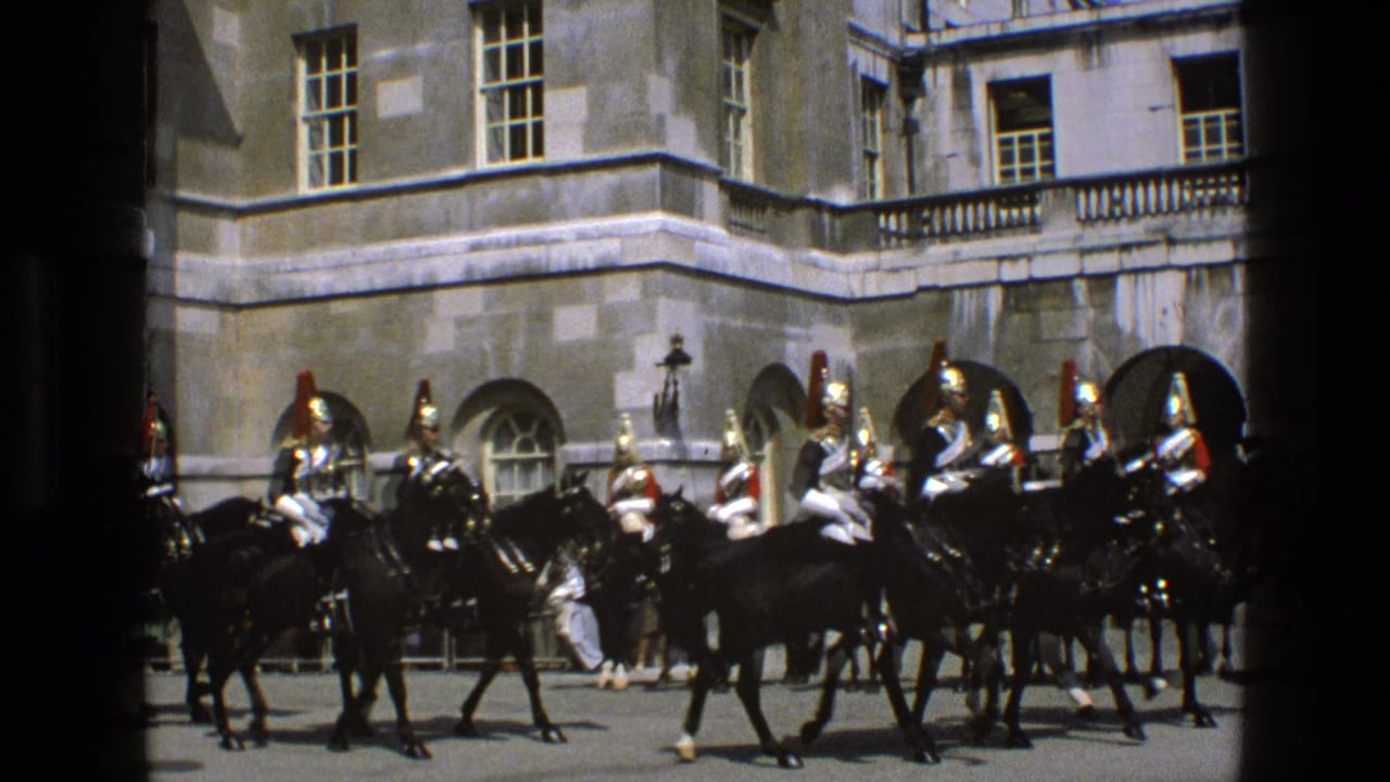Mounted uniformed guards ride black horses past a stone palace facade.