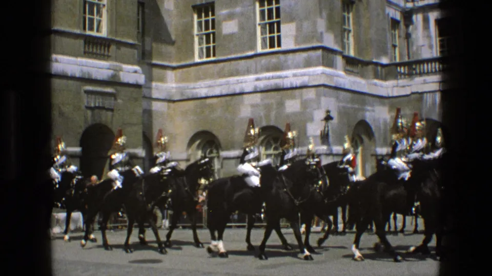 1969 England 8mm frame showing mounted ceremonial guards and black horses, partly divided by a dark film gate edge.