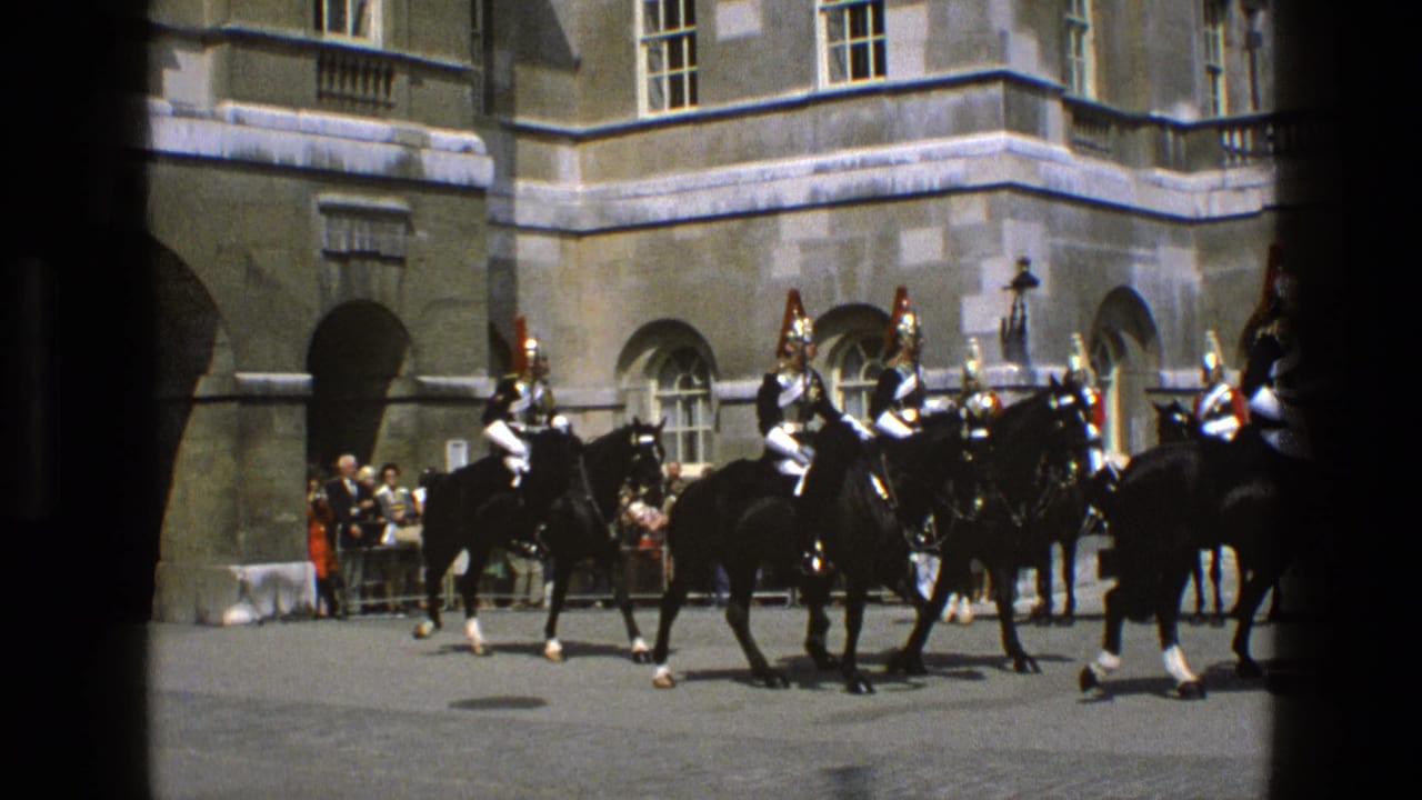Ceremonial cavalry in armor and red plumed helmets ride in formation across a courtyard in 1969 England.