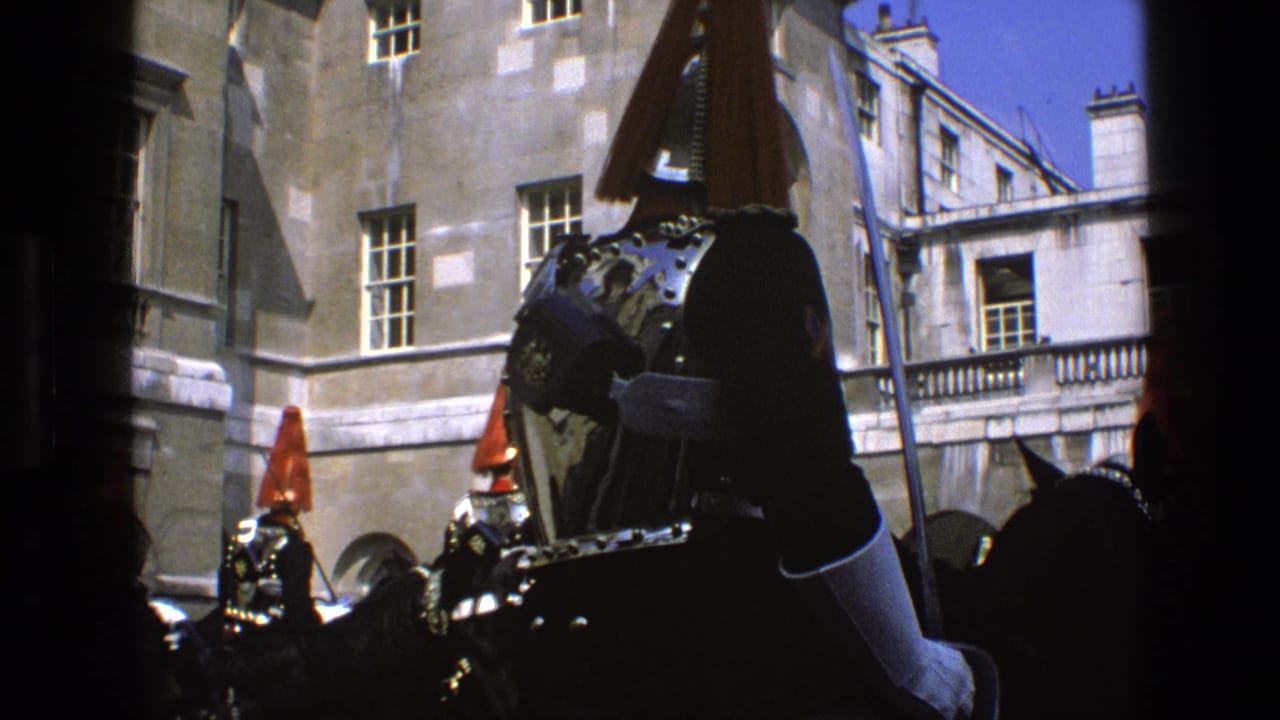 A close 1969 England home-movie view frames a mounted ceremonial guard's armor and plume with other riders behind.