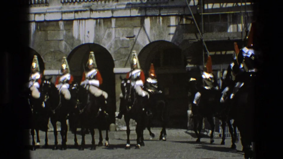 Mounted guards in plumed helmets stand in formation near stone arches, consistent with 1969 England ceremonial footage.