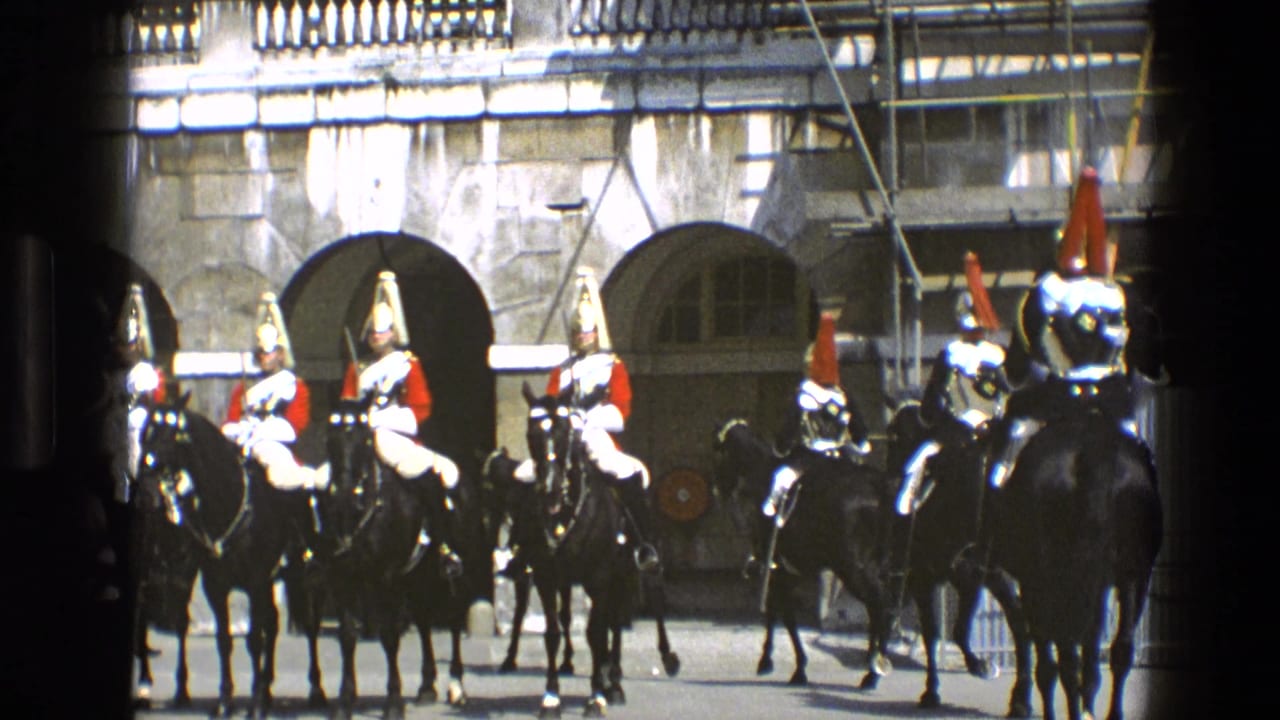 1969 England 8mm frame showing ceremonial mounted soldiers in red tunics and plumed helmets before arched stone doorways.