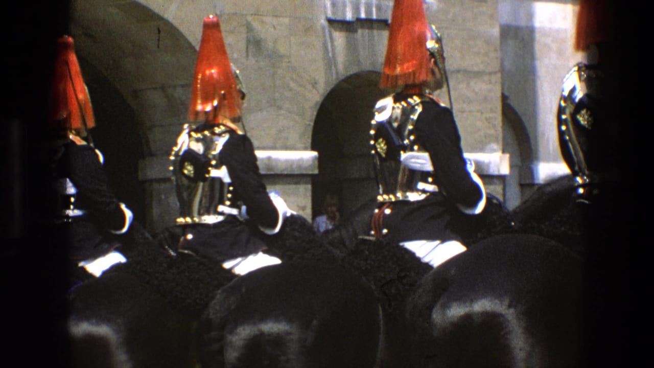 Ceremonial riders in armor and red plumes line up on horseback beside stone arches.