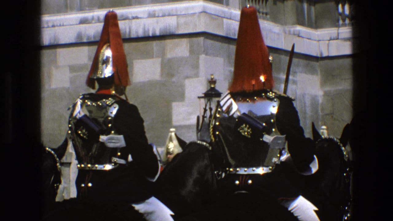 1969 England footage showing mounted ceremonial soldiers in red plumes, polished armor, and dark uniforms near stone architecture.