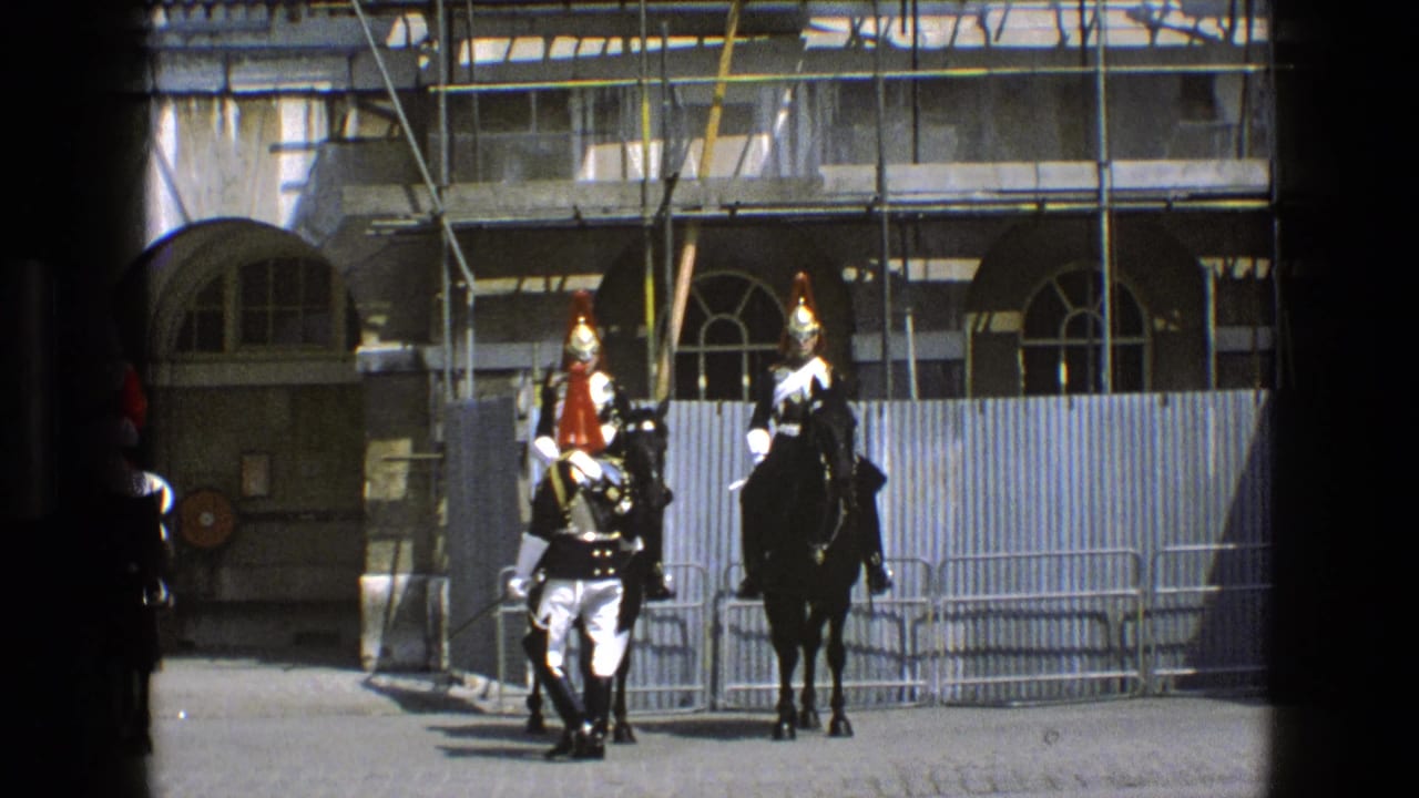 Two mounted guards and a walking soldier in front of stone arches and scaffolding.