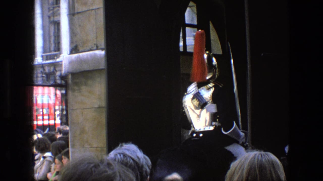 1969 England 8mm frame showing a mounted ceremonial guard in red uniform partly obscured by spectators and frame shadows.