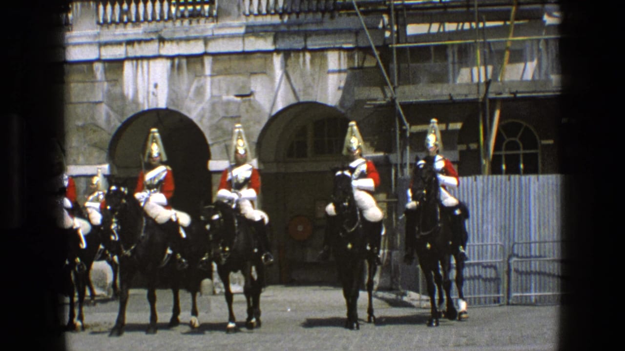 Uniformed riders on black horses stand near crowd barriers in front of arched stone openings.