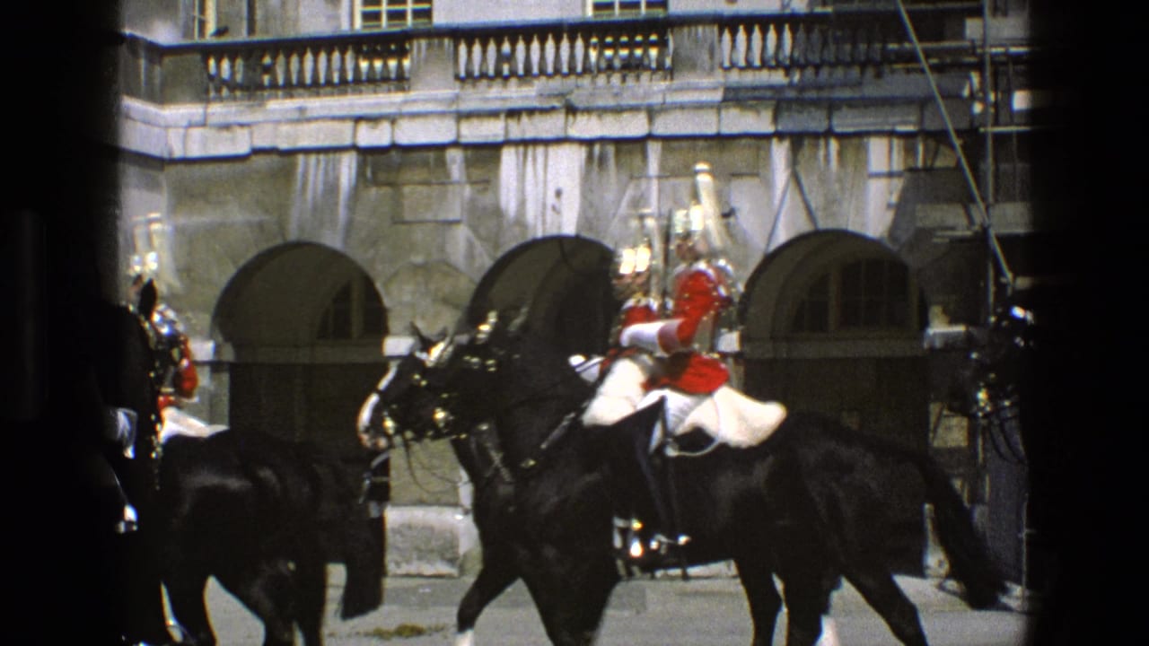 Mounted guards in red and dark uniforms ride black horses past arched stone doorways.