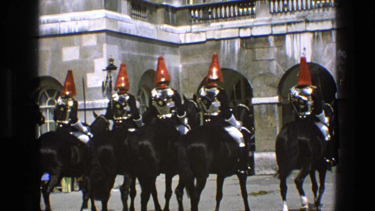 Mounted guards on black horses line up before stone arches.