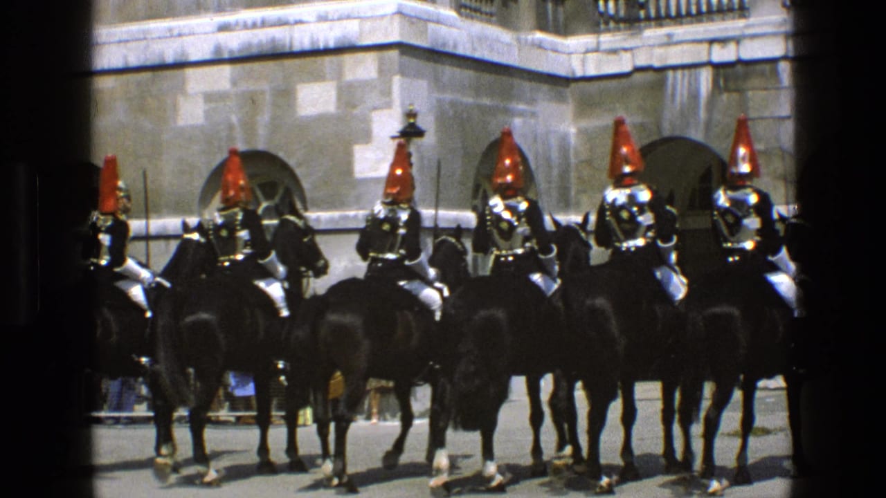 A wider 1969 England view of mounted guards in red plumed helmets on black horses, with onlookers partly visible behind them.