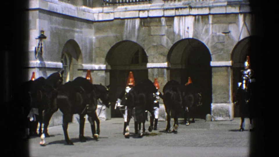 1969 England frame with ceremonial guards, black horses, and stone palace arches seen from a home-movie viewpoint.