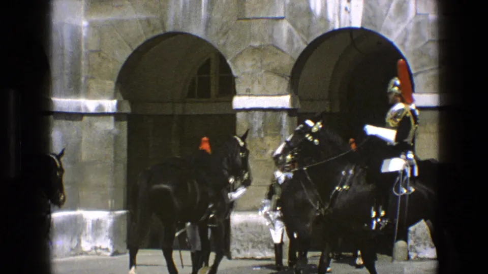 A ceremonial mounted guard on a black horse stands close to arched stone entrances in 1969 England footage.