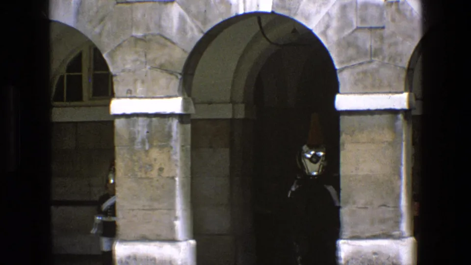 The mounted guard and horse move deeper into the shadowed archway, with the red plume faintly visible against the dark opening.