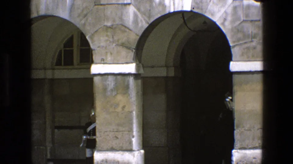 The stone arcade fills the frame as the mounted guard is nearly hidden inside the dark archway in the 1969 England scene.