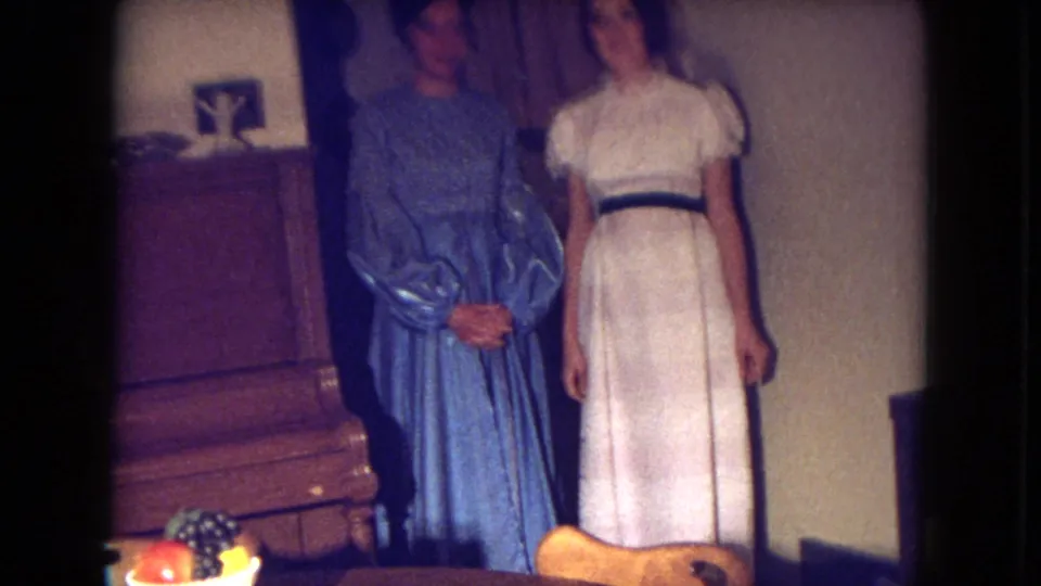 The women stand side by side near furniture and household items, with the 1969 Fort Wayne 8mm frame showing soft focus and warm interior light.