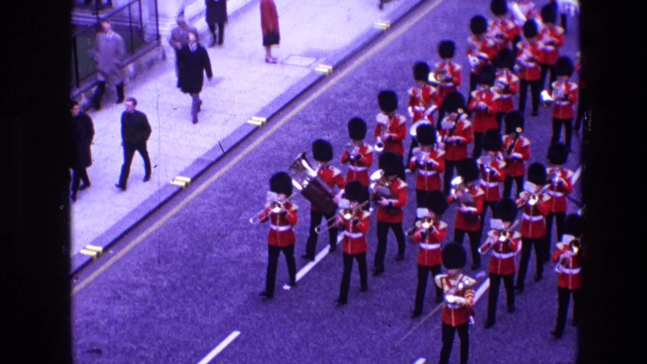 Marching band musicians in red uniforms play brass instruments in the street.