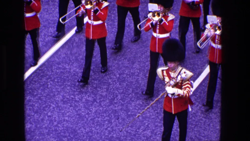 1969 Ireland parade frame showing a uniformed leader with a mace or staff before red-coated brass musicians.