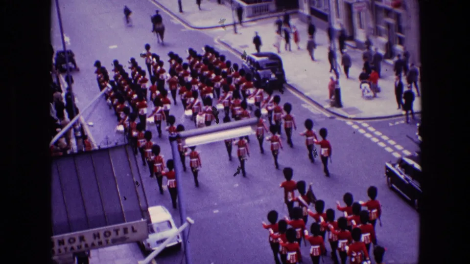 Elevated 1969 Ireland view of a ceremonial guard formation crossing a city intersection with pedestrians and vehicles around it.