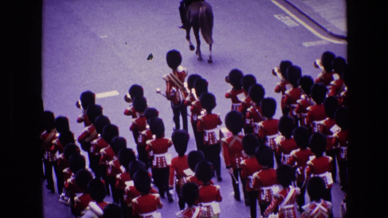1969 Ireland home-movie frame showing a British military band in red tunics and tall black hats marching behind a horse.