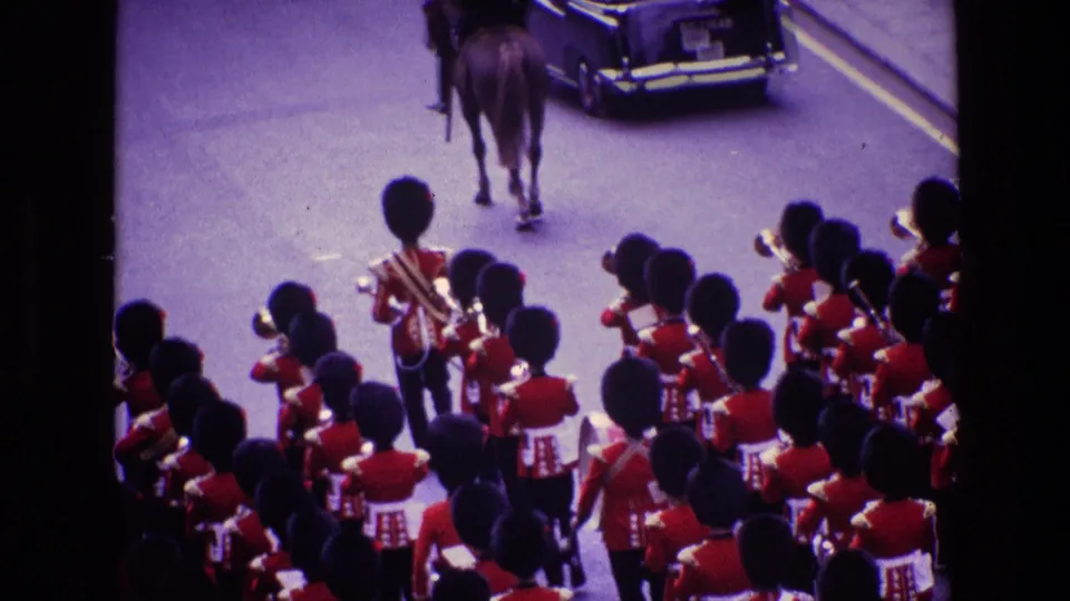 8mm frame of a British military band in Ireland following a horse and vintage car in a ceremonial parade.