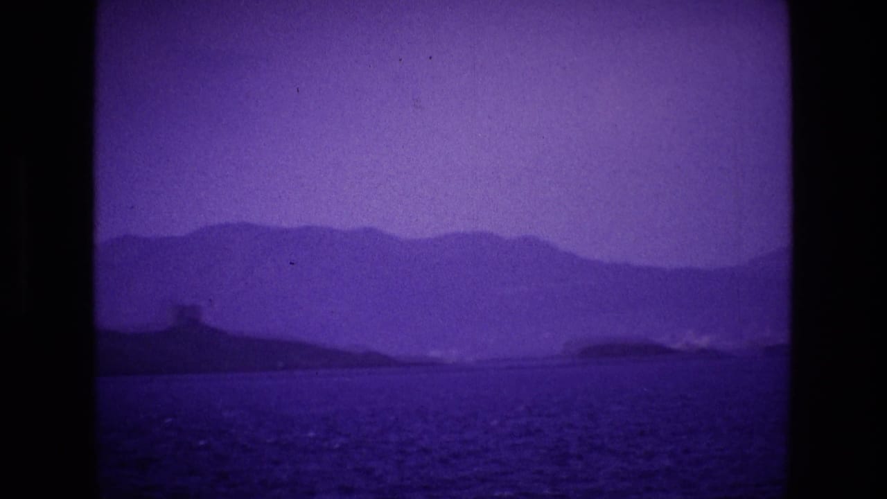 Purple-tinted sea view with distant hills and a low shoreline across the water.