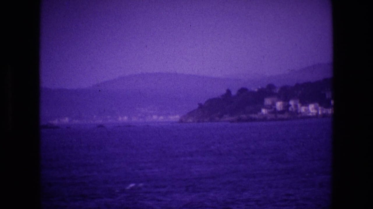 Distant headland with white buildings beyond a purple-blue stretch of water.