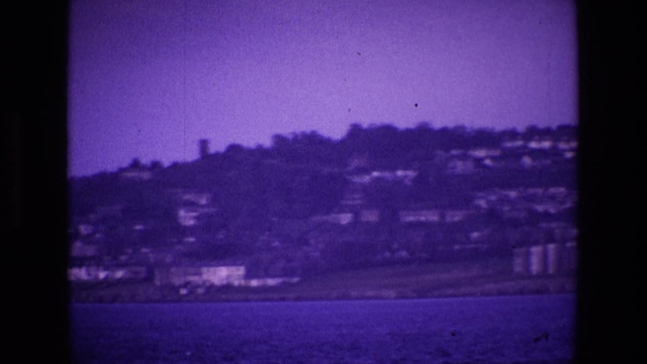Distant hillside town across open water with dark 8mm frame edges.