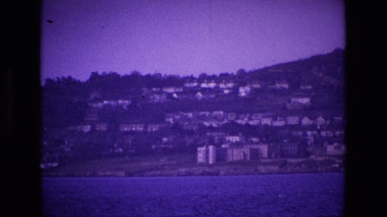 Coastal hillside with clustered houses and waterfront buildings beyond the sea.