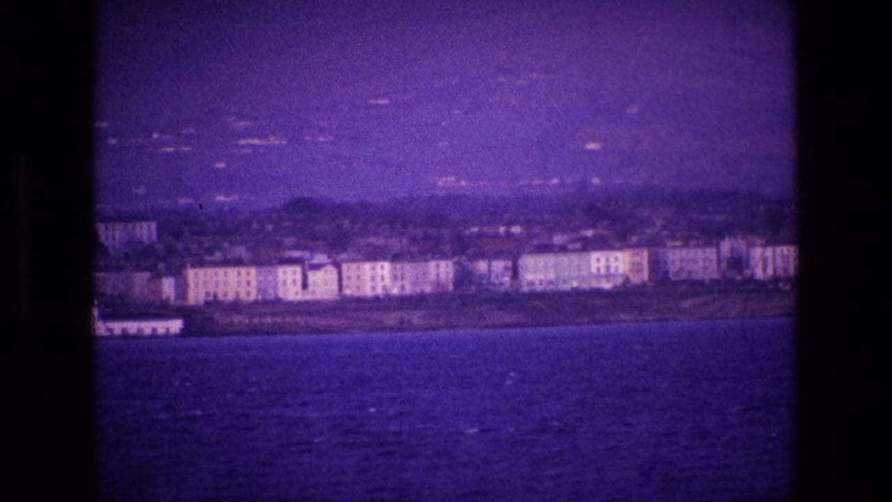 Distant shoreline buildings and hills viewed across the sea through an 8mm frame.
