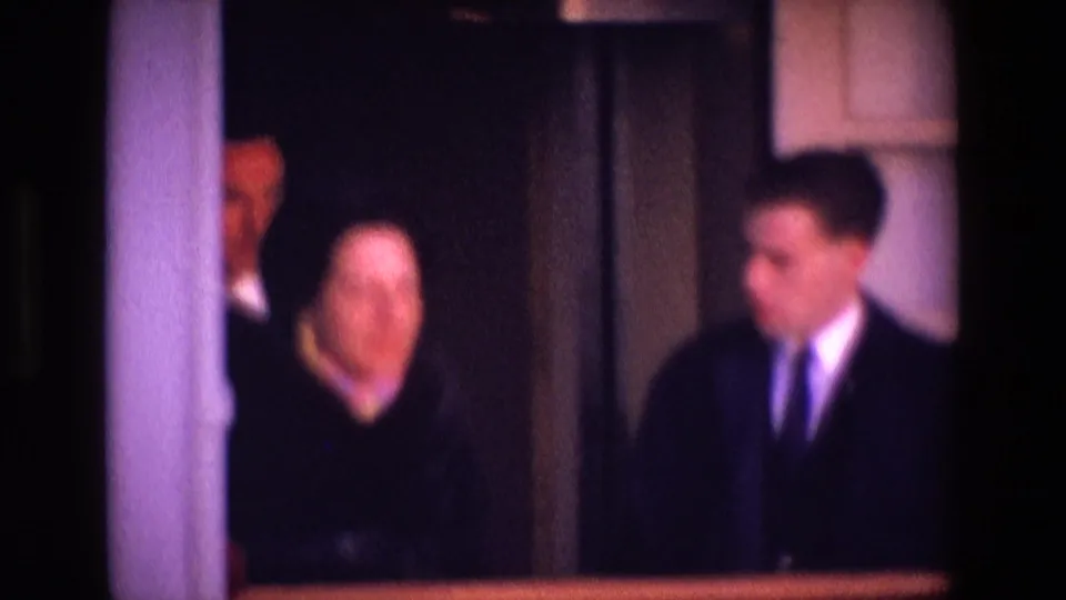 The final frame shows a woman beside a suited man, with another suited figure partly visible in the dim 1969 Ireland interior.