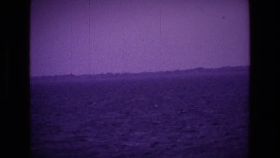 1969 Irish 8mm frame showing open water and a low distant shoreline through a purple color cast.