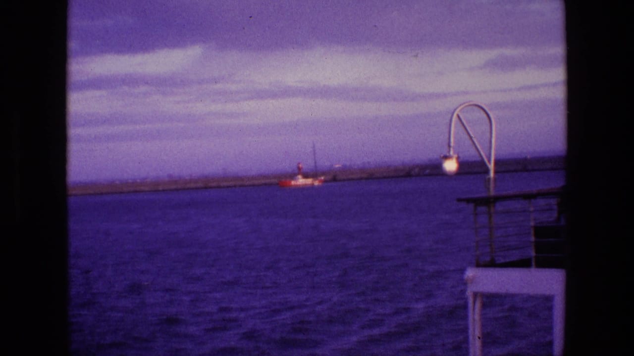 Open water with a red-and-white boat near a breakwater and a curved lamp at right.