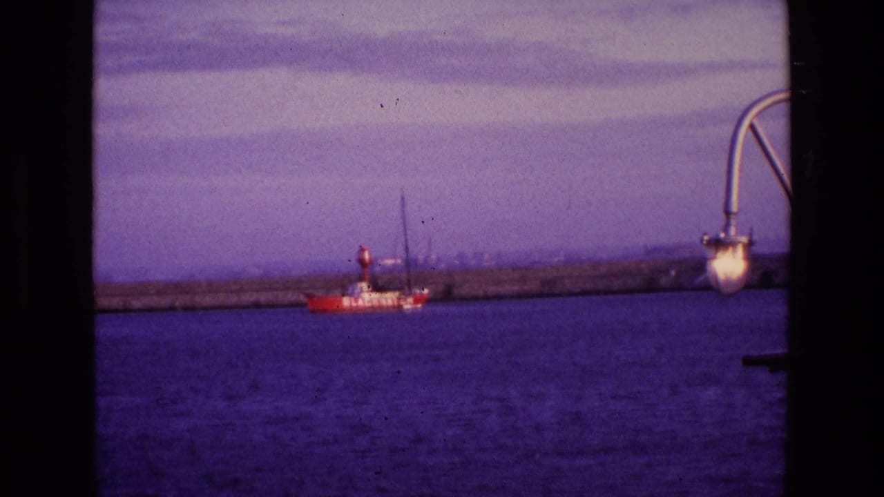 Red boat marked BLACKWATER on harbor water near a stone wall.