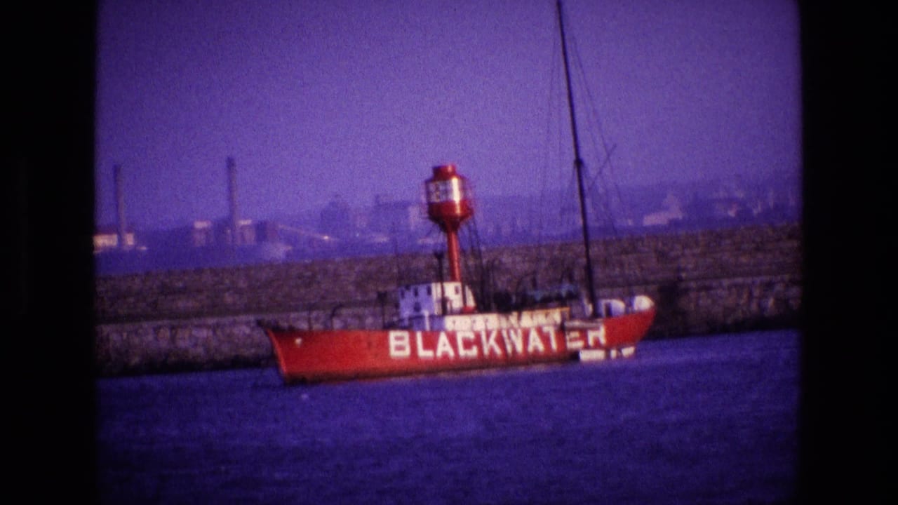 1969 Ireland harbor view with the BLACKWATER name clear on a red vessel, set against a stone quay and distant industrial waterfront.