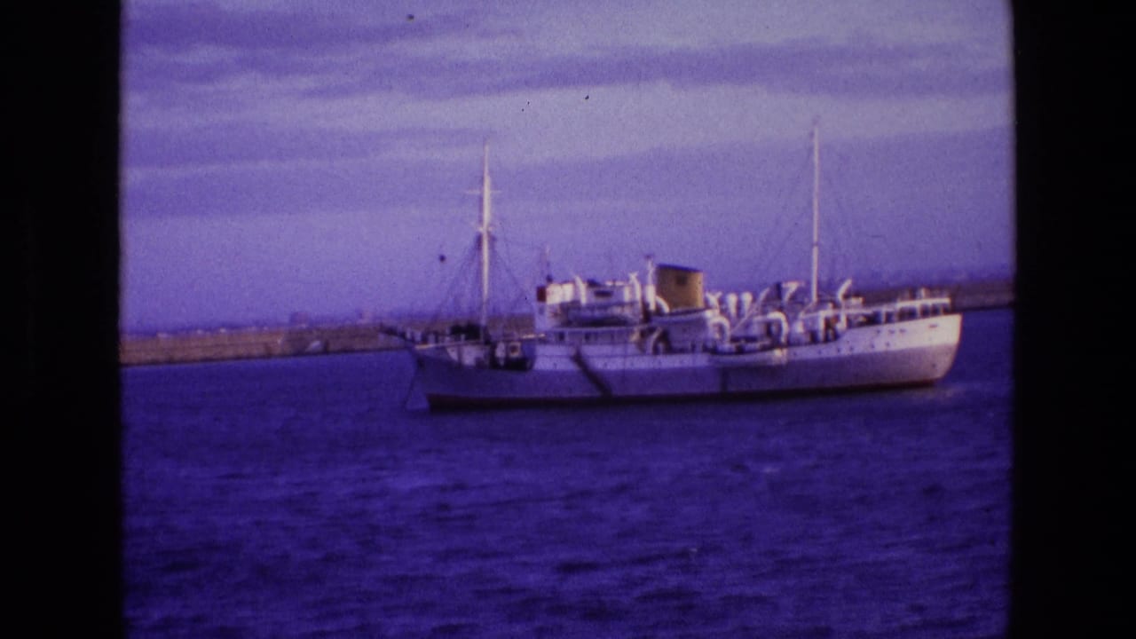 A large white ship sits at anchor in Irish waters in 1969, filmed from shore with masts and deck equipment visible.