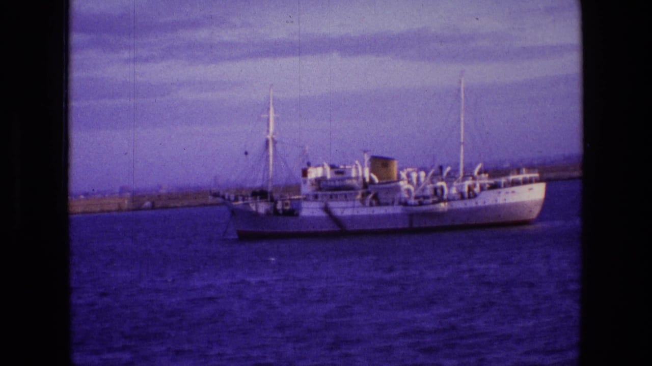 The 1969 Irish home-movie frame shows the same white vessel in profile, with rigging, funnel, and shoreline behind it.