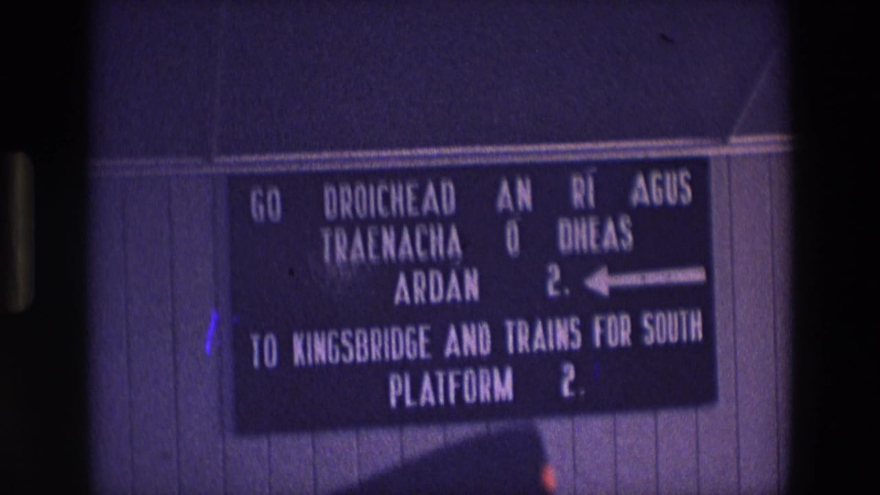 1969 Ireland 8mm frame showing a bilingual station sign directing passengers to Kingsbridge and southbound trains via Platform 2.