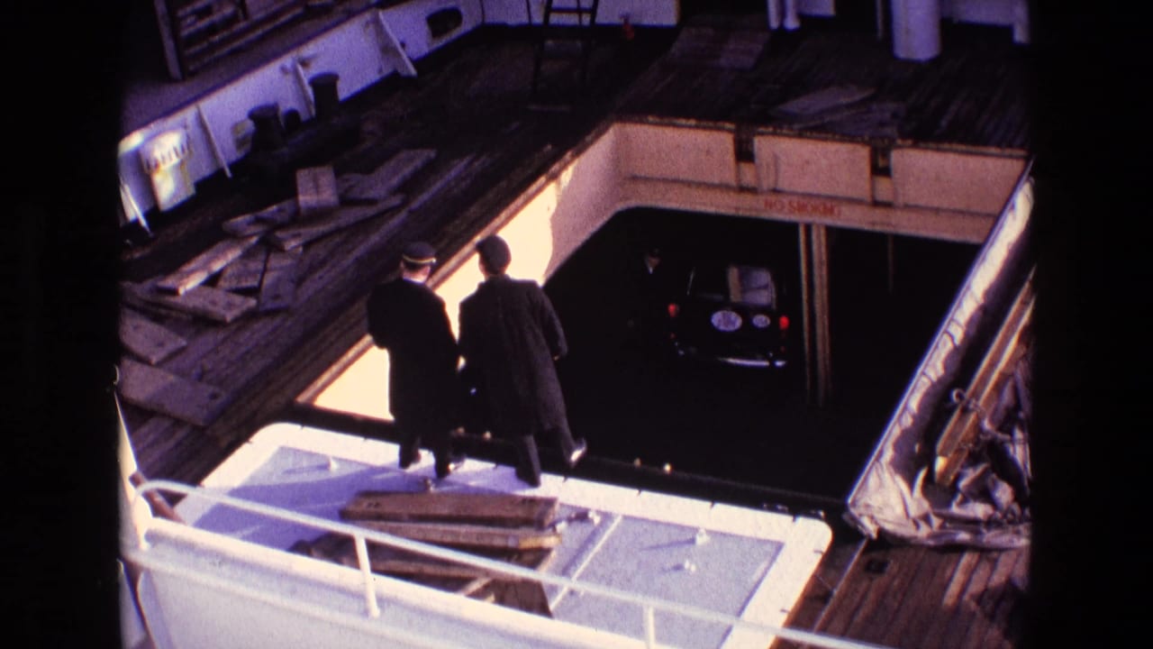 1969 Ireland ferry-deck view with two adults near the rail and a small black car in the lower loading area.